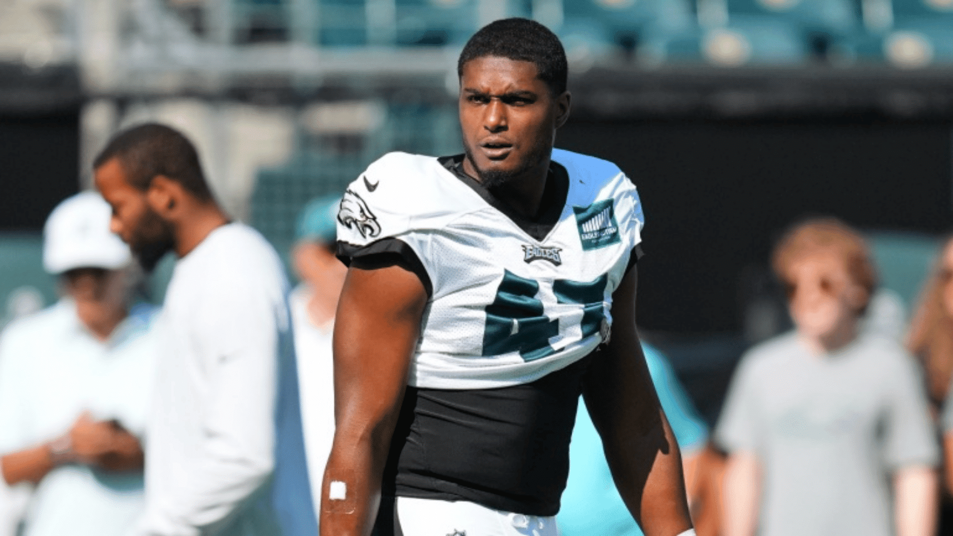 a football player in a white eagles number 45 jersey stands on the field with blurred people and stadium seats behind him
