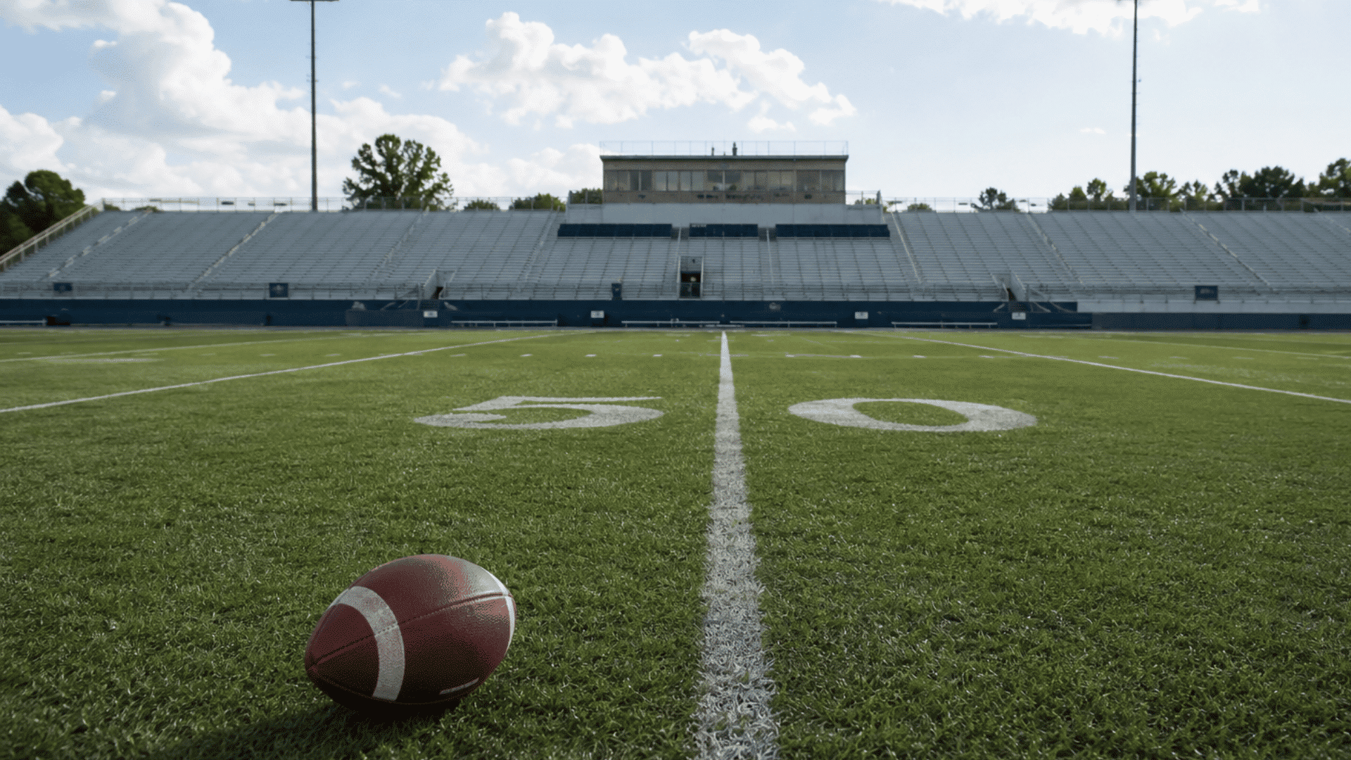 american football field with a football on the turf under cinematic stadium lighting