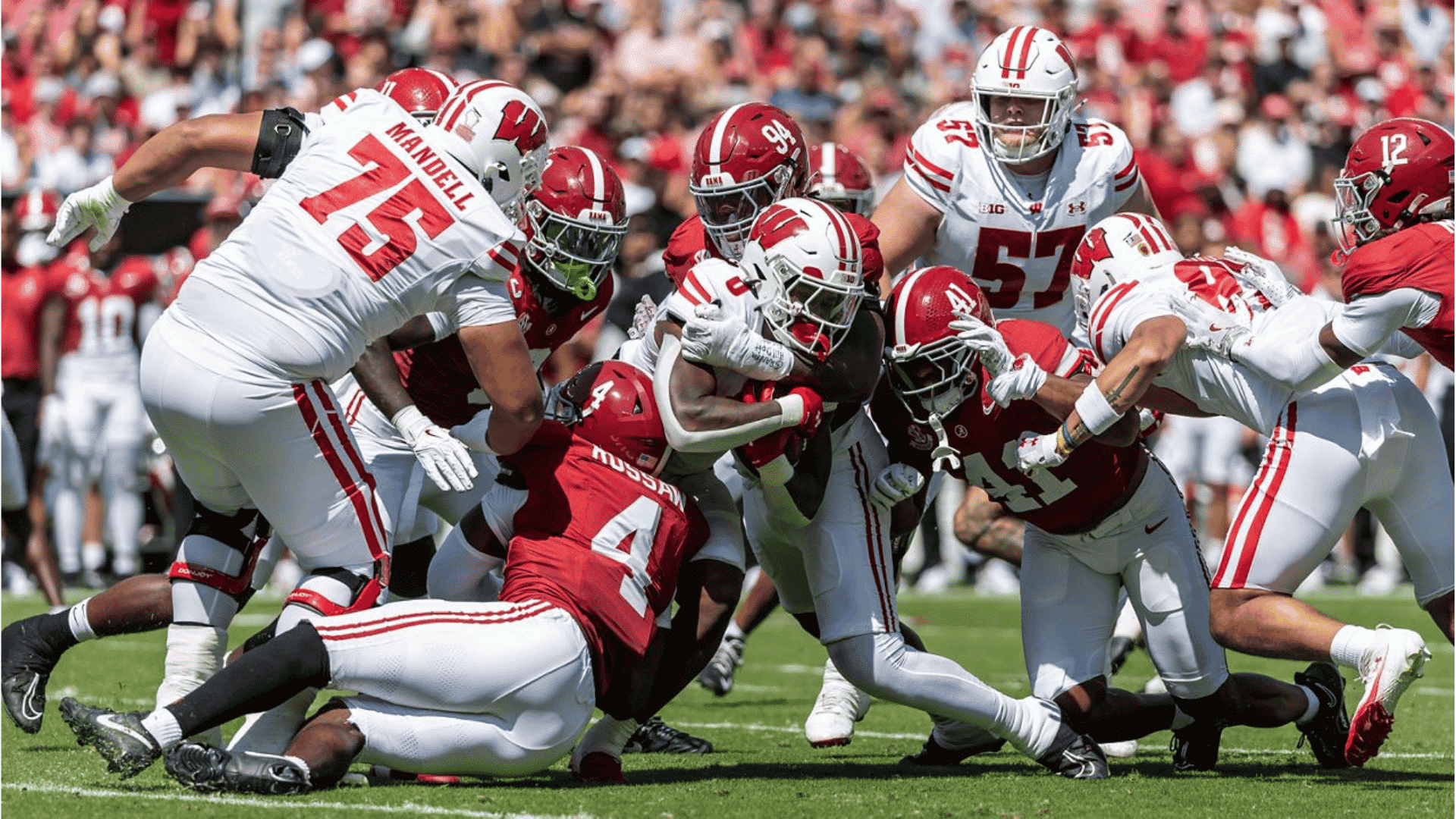 american football game in action showing a player being tackled by multiple defenders in red uniforms