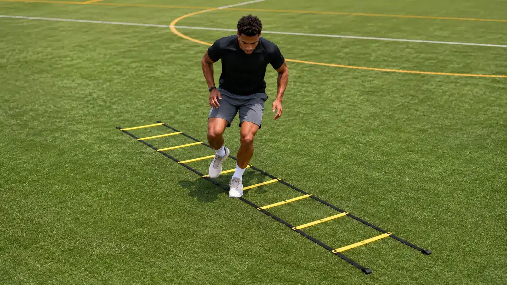 athlete doing quick footwork through an agility ladder on turf during a speed and agility training session