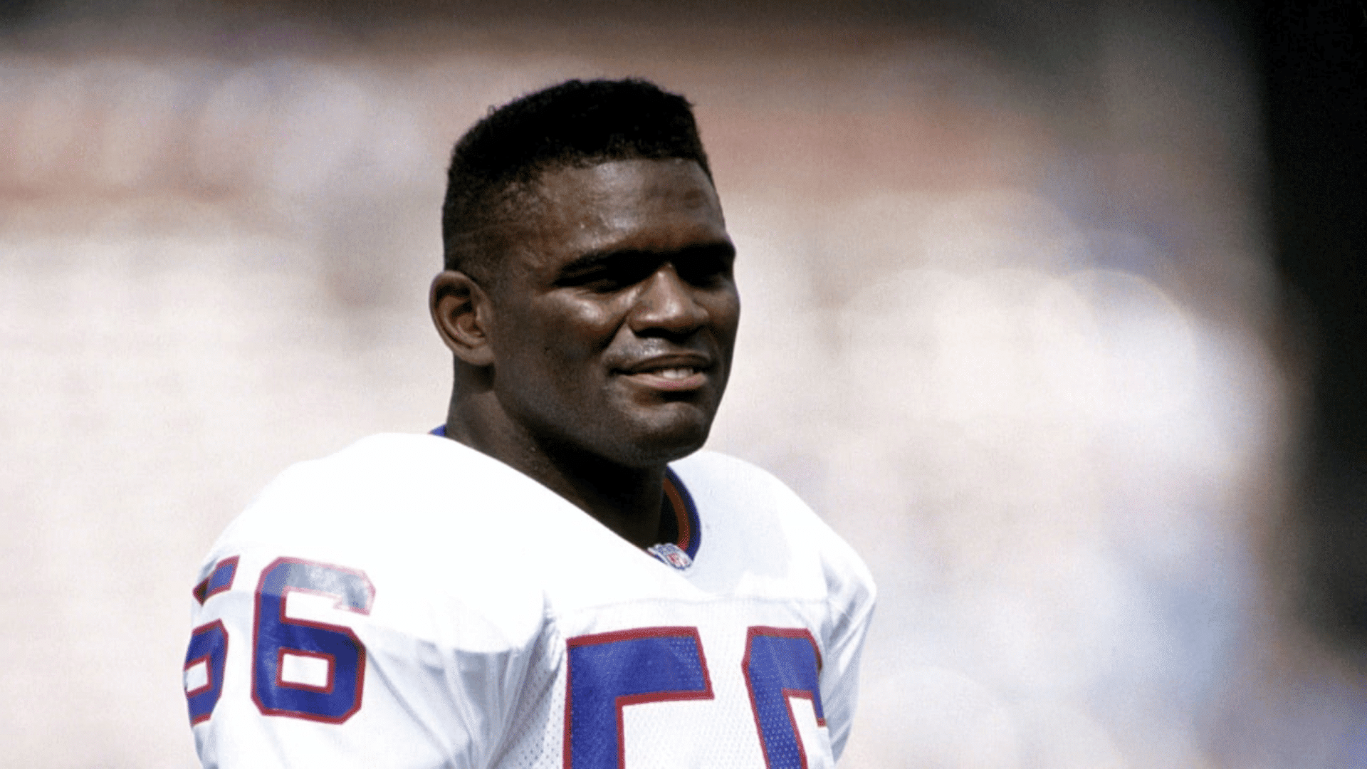 black and white photo of a football player wearing white jersey number fifty six standing on the field
