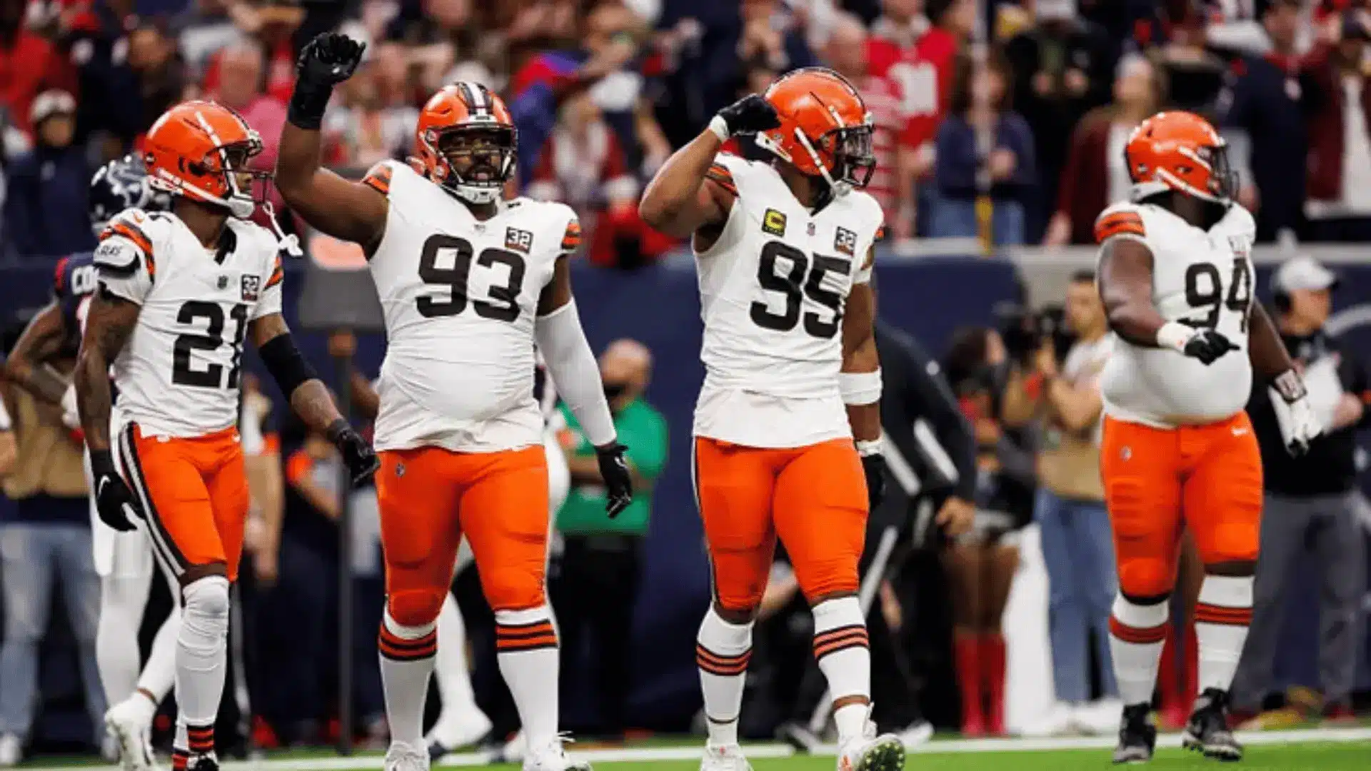 cleveland browns defenders in white uniforms celebrate on the field during a game in front of blurred fans