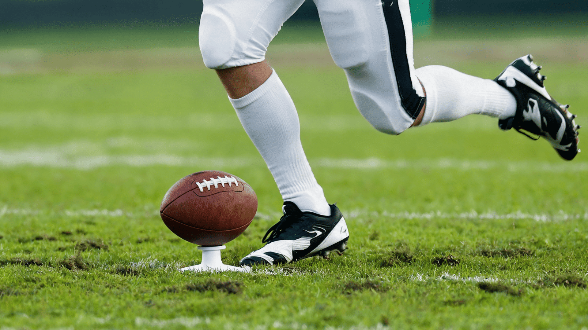 close view of the support foot planted beside the football as the kicking leg begins its forward swing