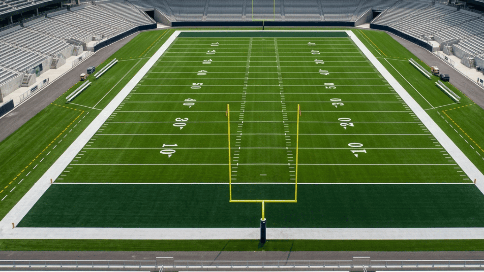 empty football stadium with marked field goal posts and numbered yard lines viewed from stands