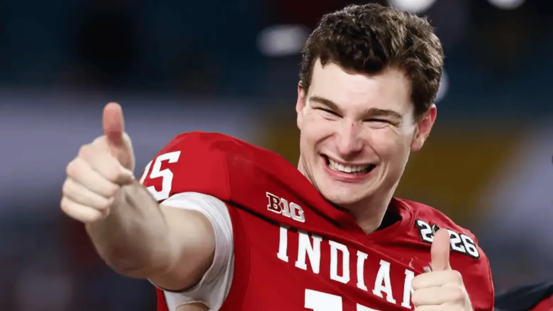smiling football player in a red indiana jersey gives two thumbs up during a game inside a stadium