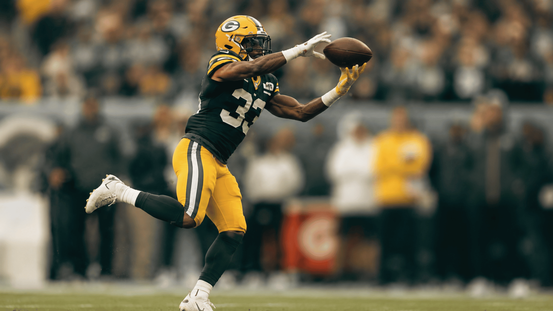 football player reaching for a catch near the sideline during game action
