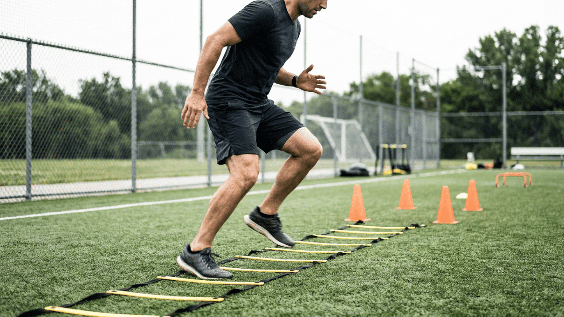 football player running an agility ladder drill on a turf field with cones nearby