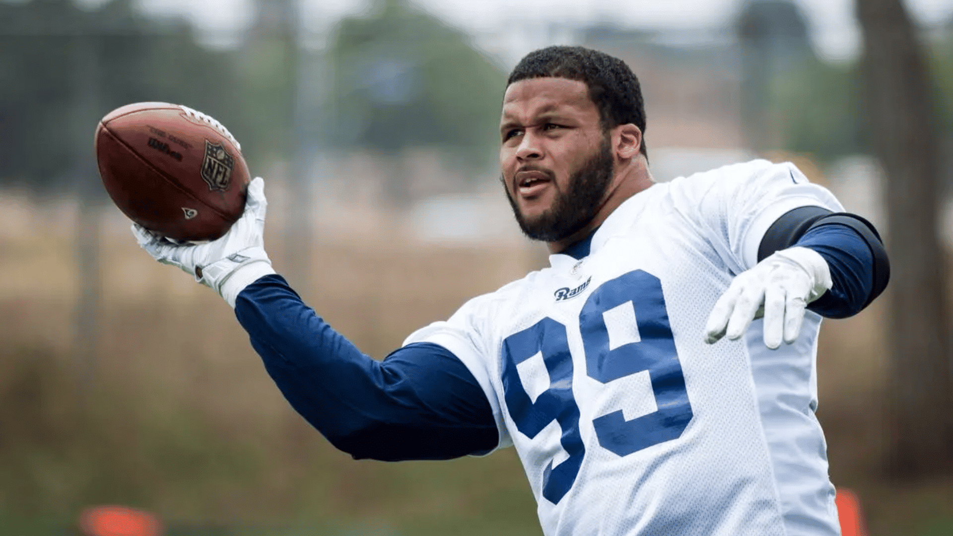football player wearing a white practice jersey with number ninety nine getting ready to throw a football