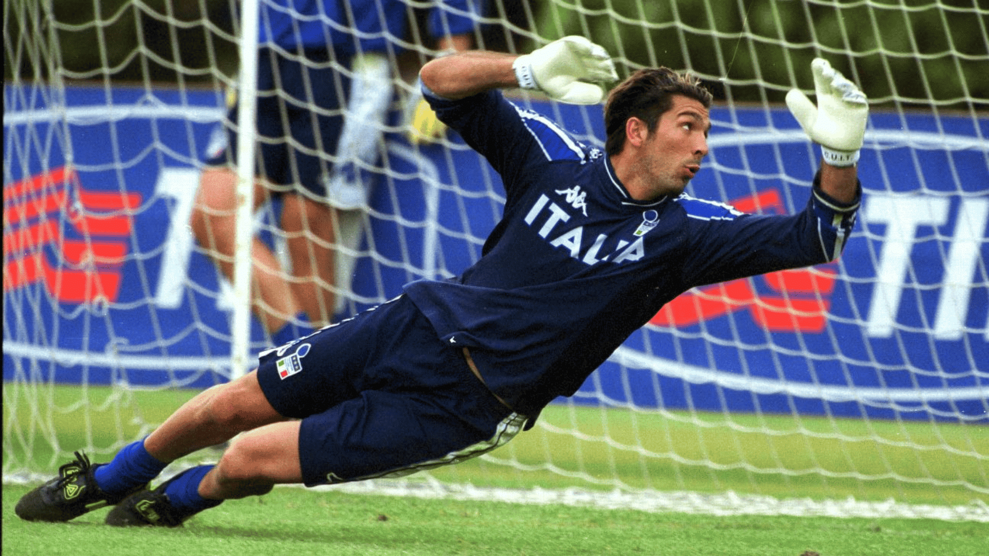gianlugi buffon attempting to save a goal by diving to the left wearing his italia jersey