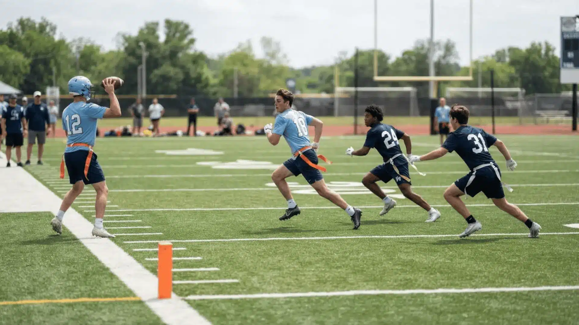 a flag football quarterback in a blue jersey throws as three players run routes across a sunny turf field