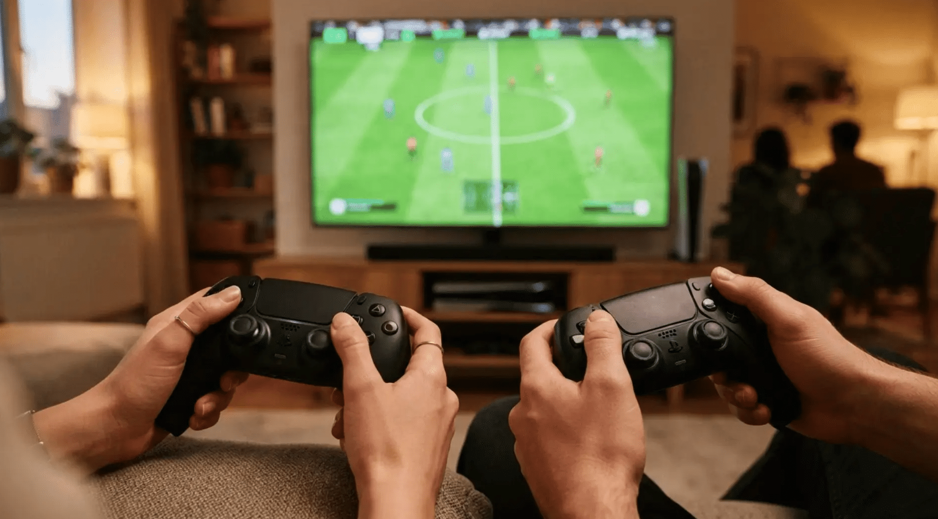 hands holding game controllers as a sports video game plays on tv for video game fantasy football names