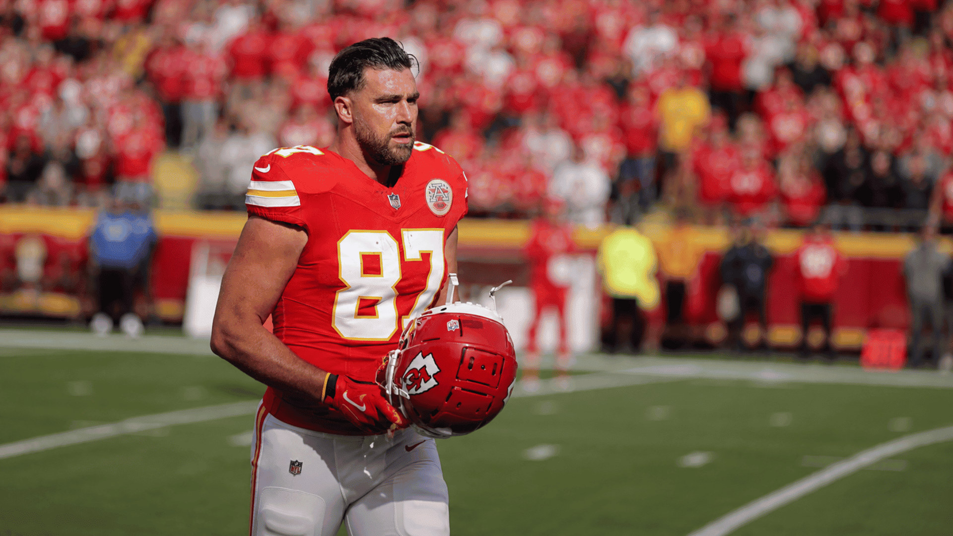 kansas city chiefs tight end walks along the sideline holding his helmet before the start of a football game