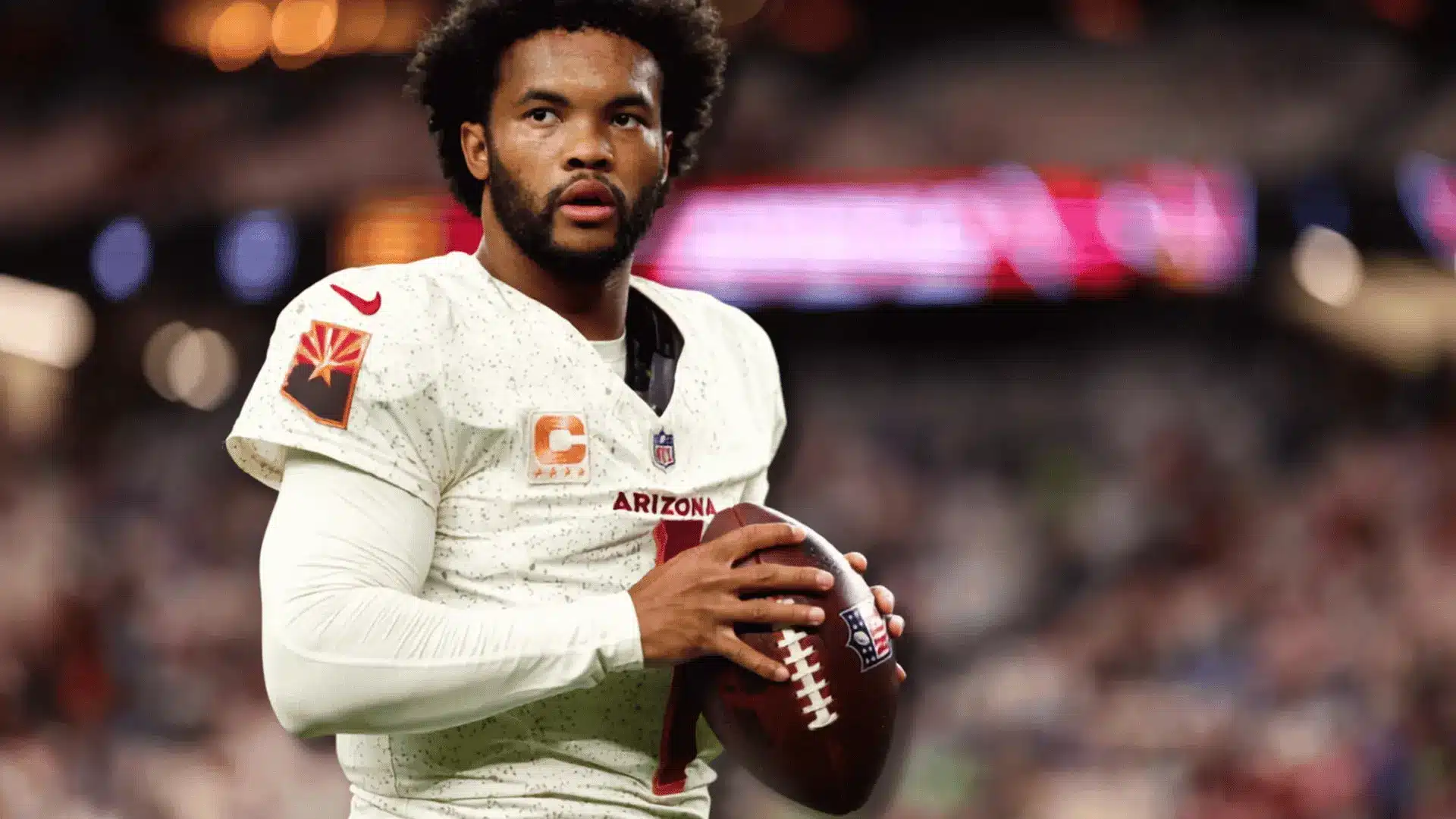 kyler murray holding a football while wearing an arizona cardinals jersey during a game