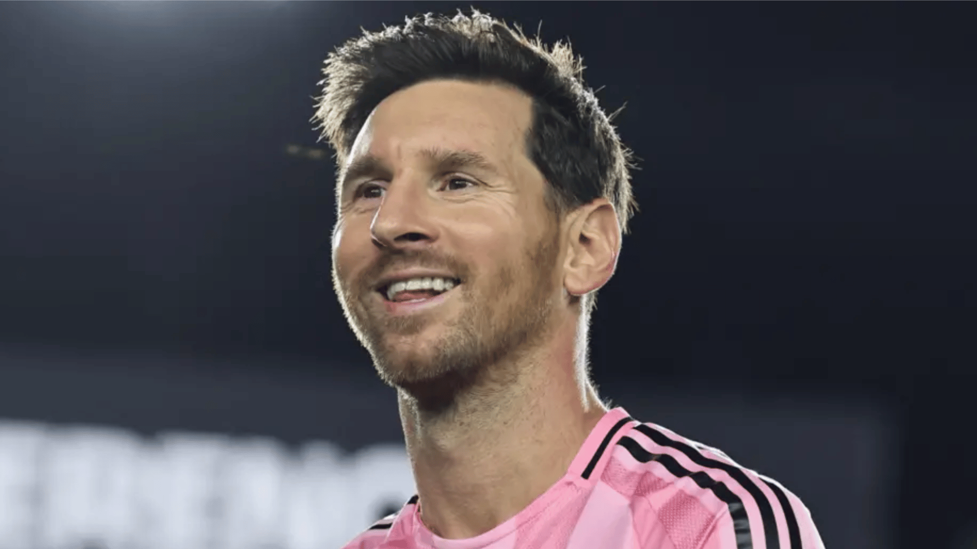 lionel messi smiling in an inter miami jersey during a match under stadium lights