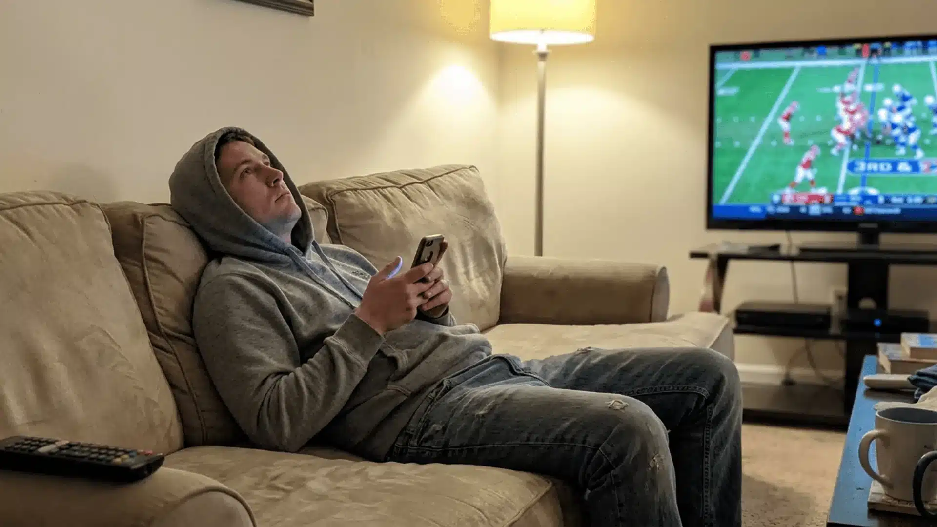 fantasy football player pondering while typing a fantasy name on a mobile app at home