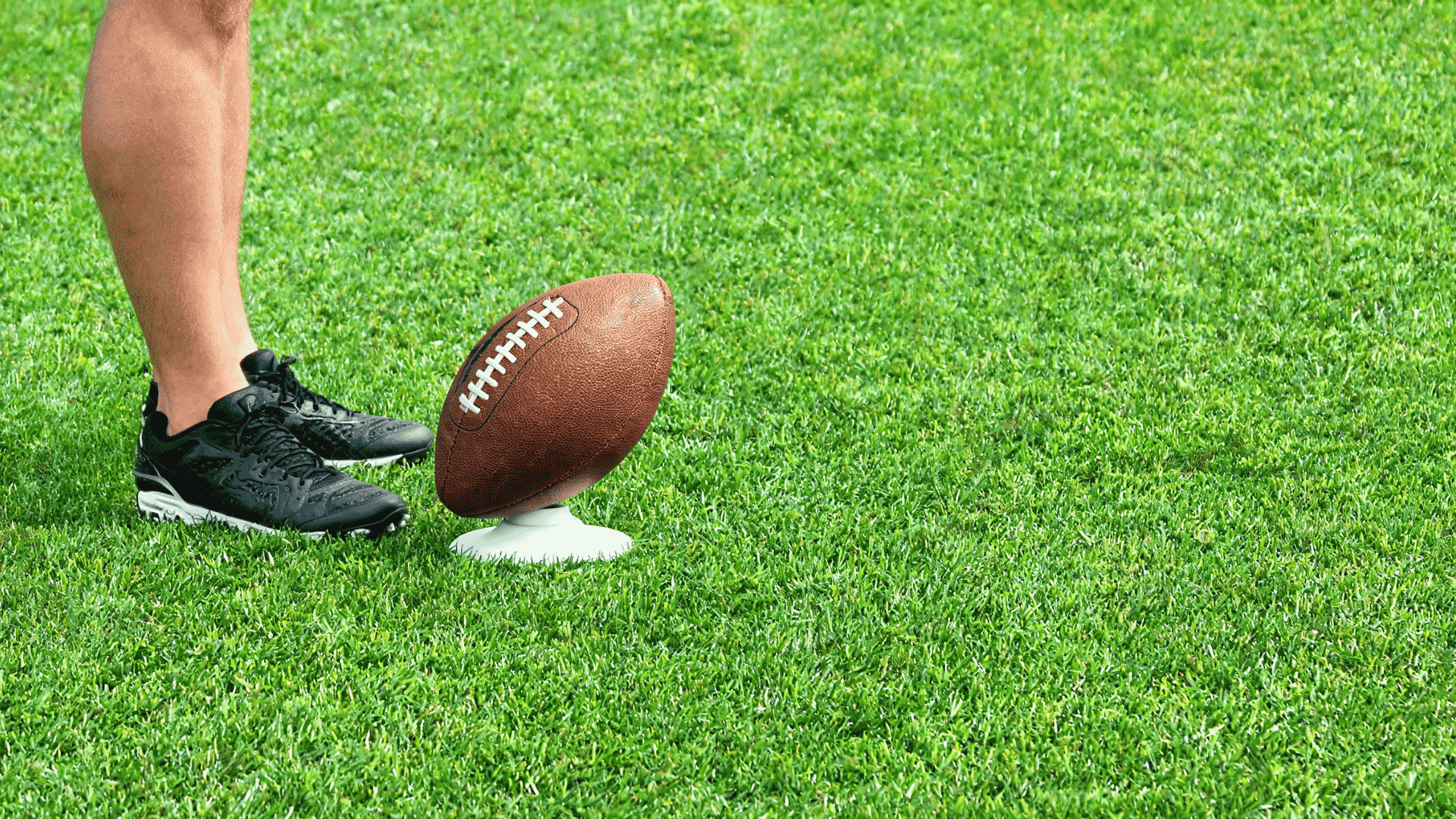 overhead close view of a support foot placed beside and slightly behind an american football on a tee