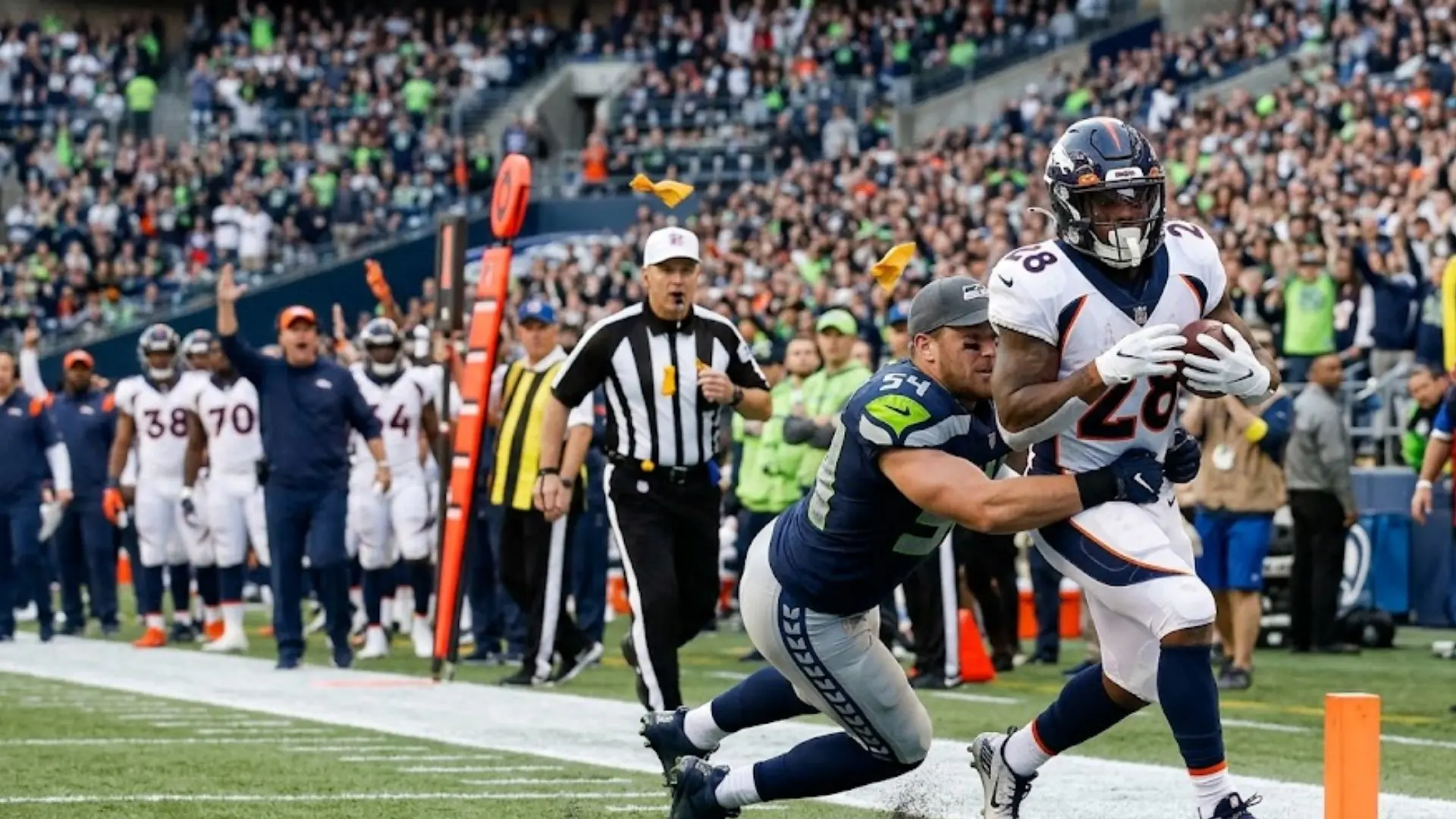 broncos running back stretches for pylon as seahawks defender attempts diving tackle near goal line