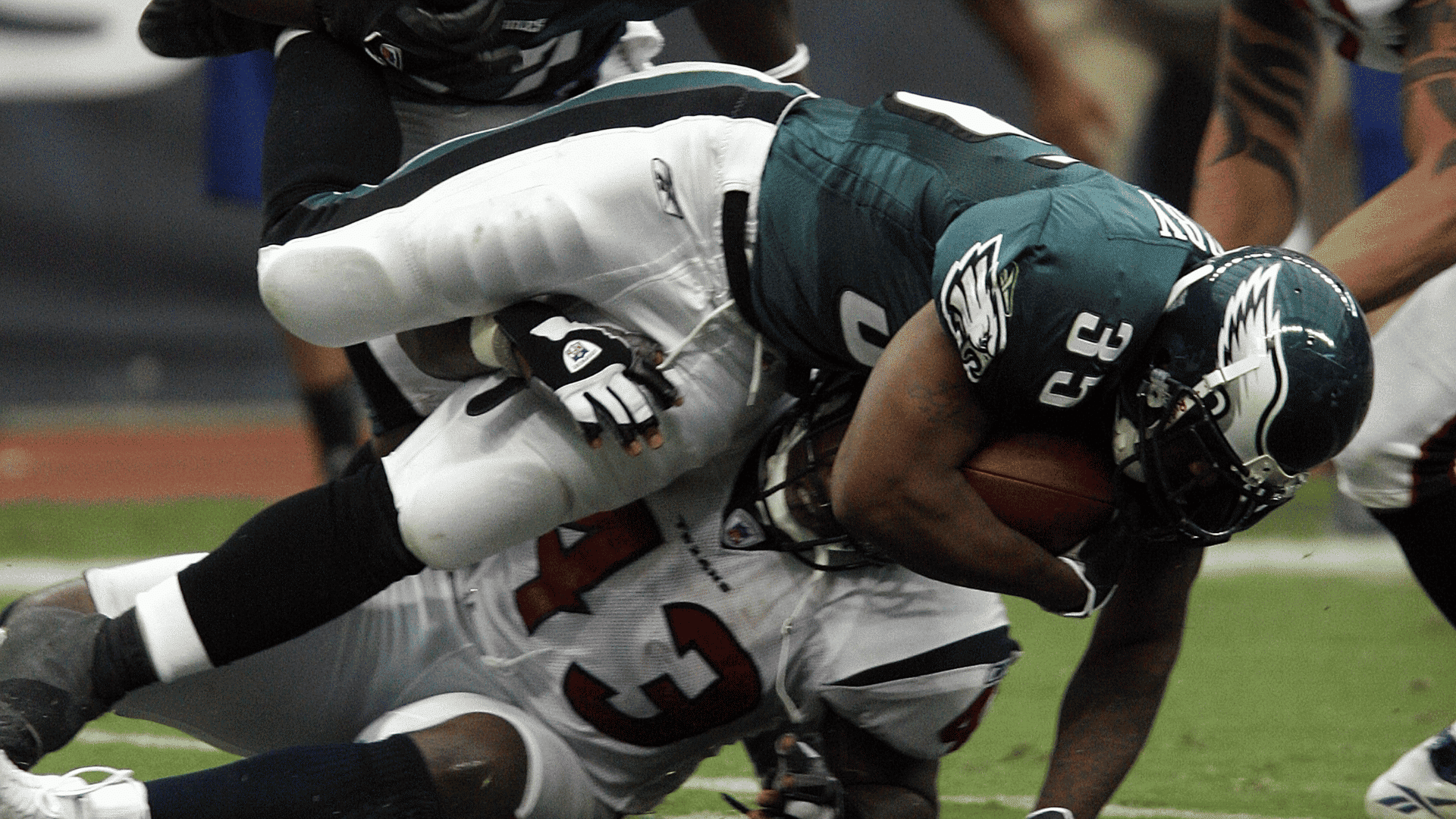 philadelphia eagles player carrying football while being tackled by a houston texans defender