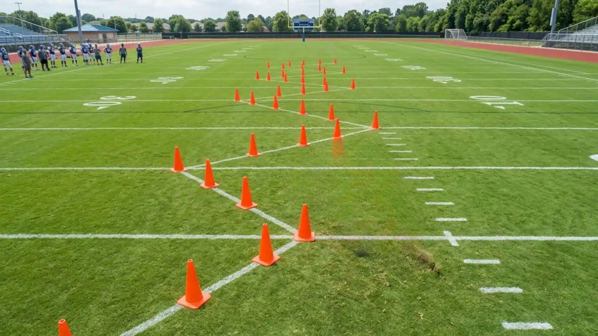 player leans low while running a cutting drill through an orange cone pattern on the practice football field