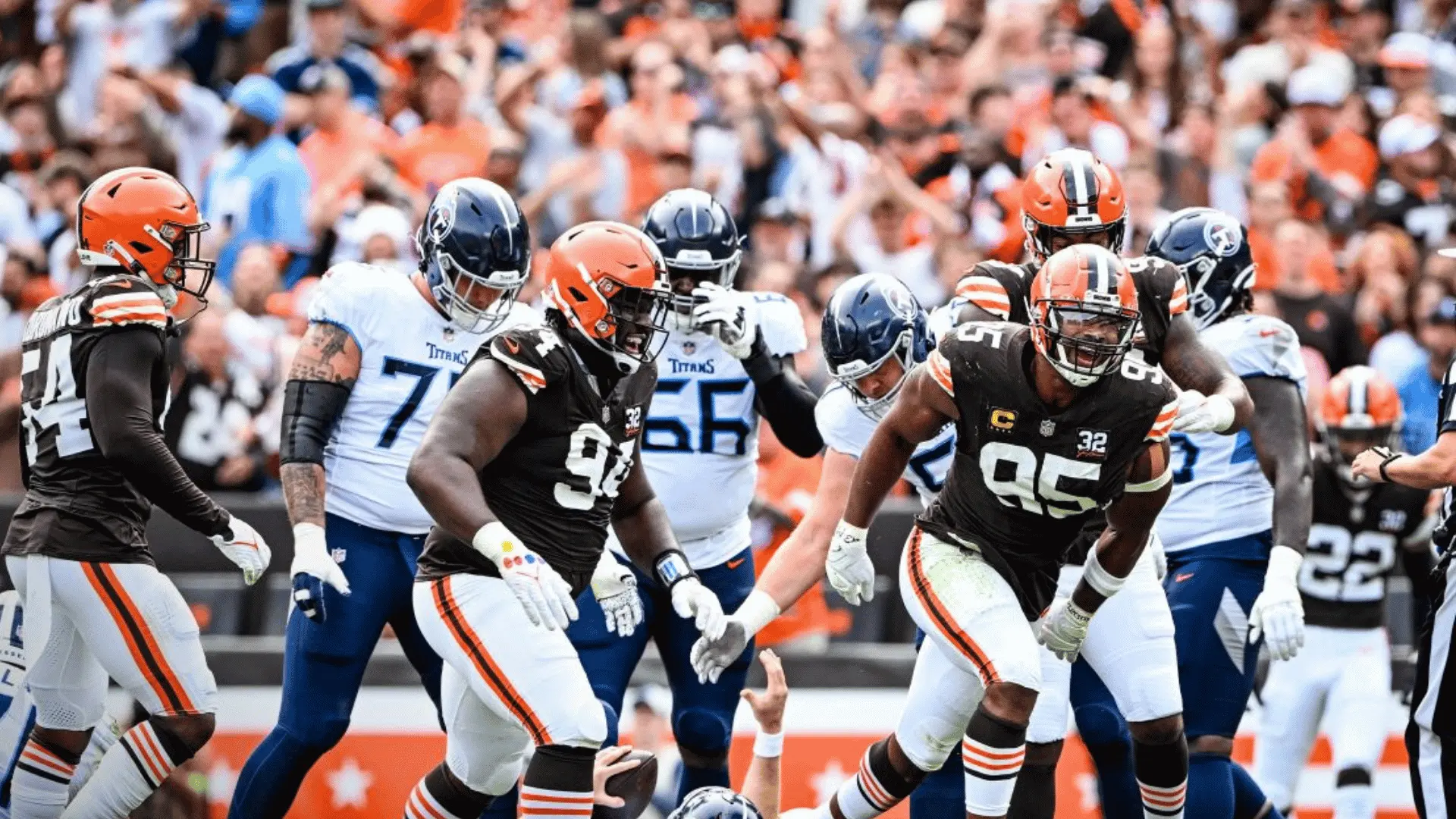cleveland browns defenders run across the field after a play against tennessee titans players as fans cheer