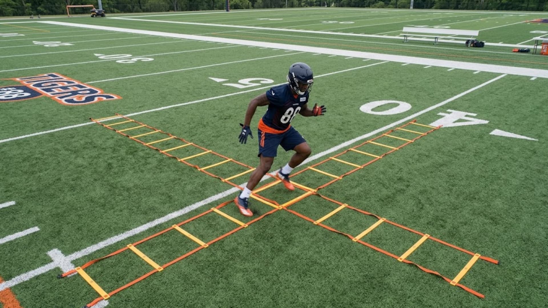 player runs through agility ladder drill wearing helmet and pads during practice on field