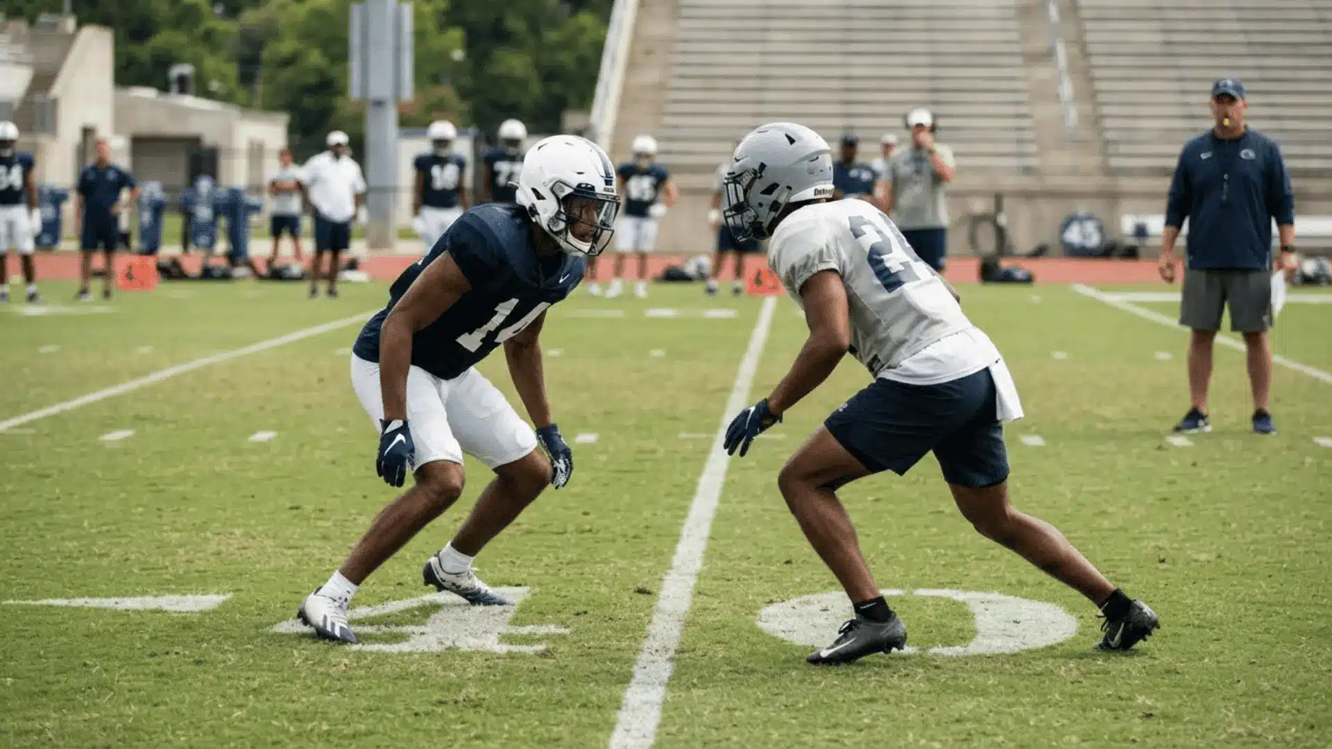 football players in blue and white practice uniforms face each other during a coverage drill on a grass field