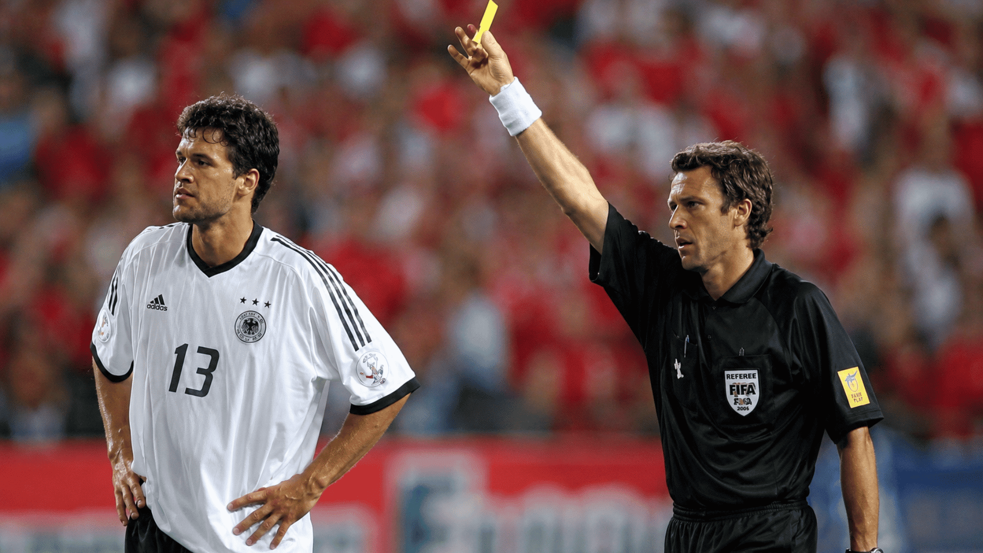 referee issuing a yellow card during a tense international soccer match as players from both teams react to the decision