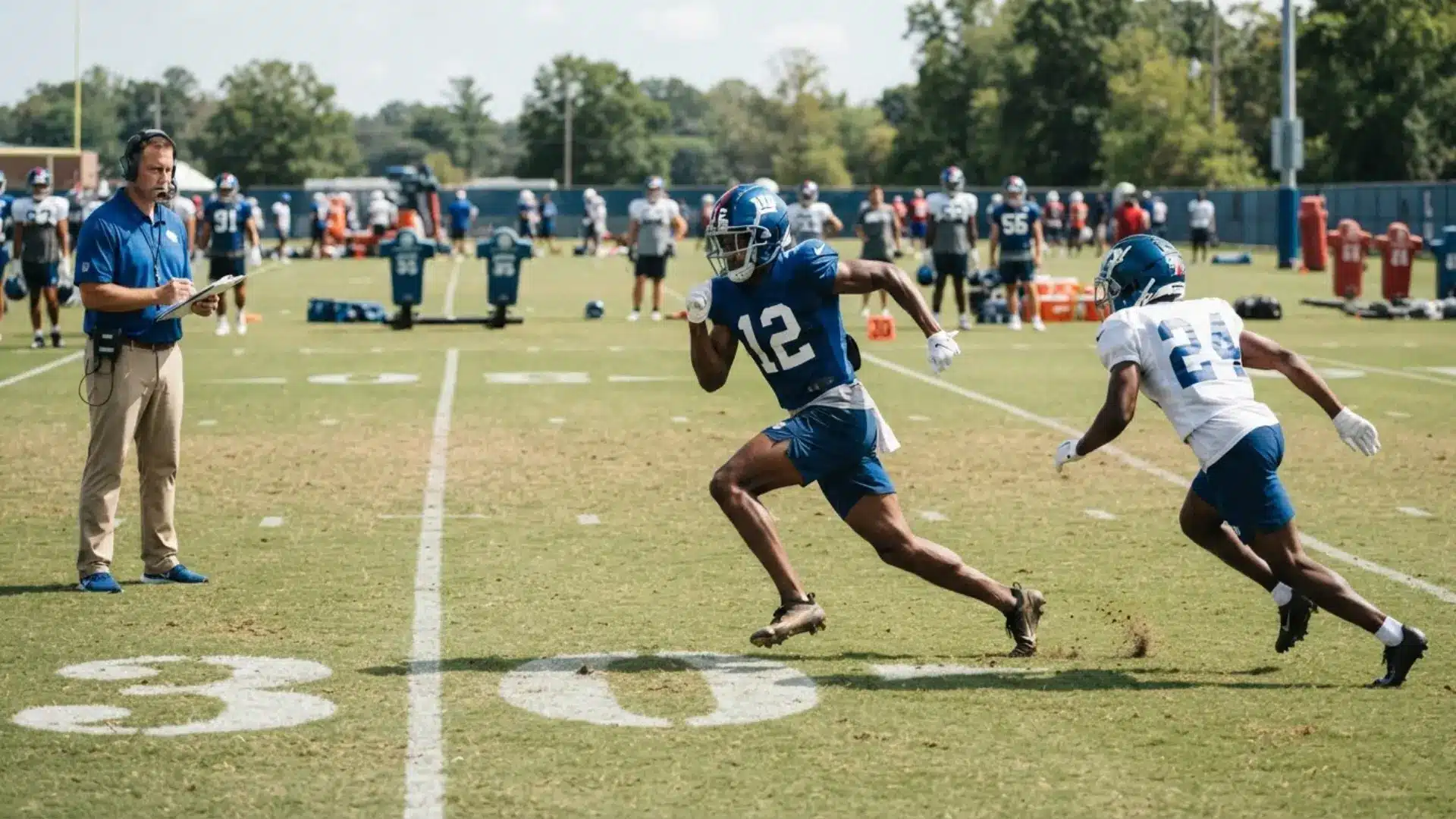 receiver runs a go route during practice as a coach watches and a defender trails across the field in drills