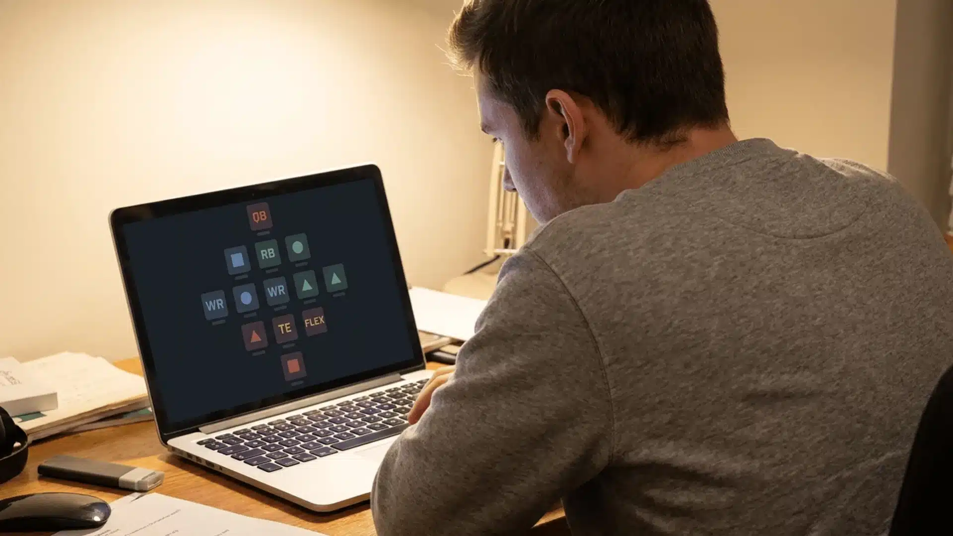 man reviewing his fantasy football roster on a laptop showing qb rb wr te and flex position slots