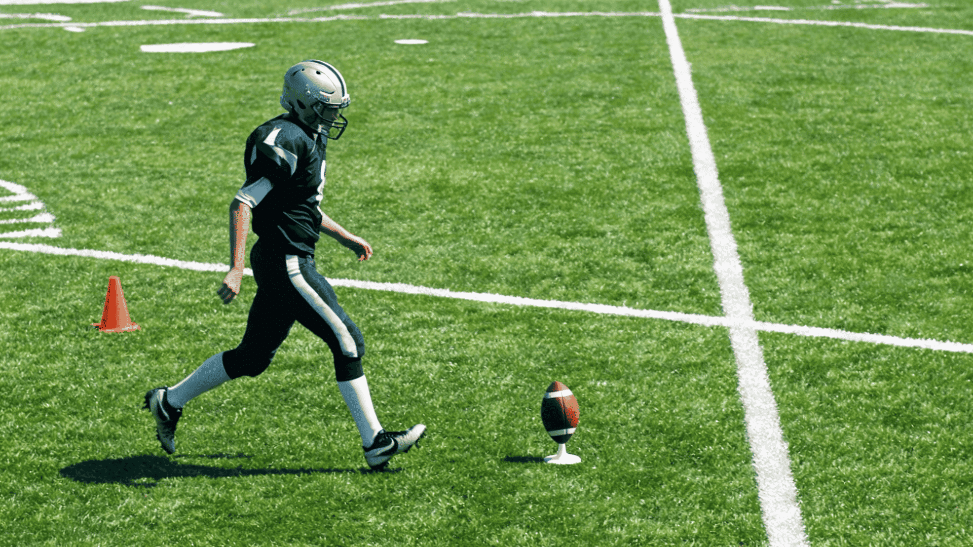right footed football kicker taking a smooth angled approach toward a ball on a tee during practice