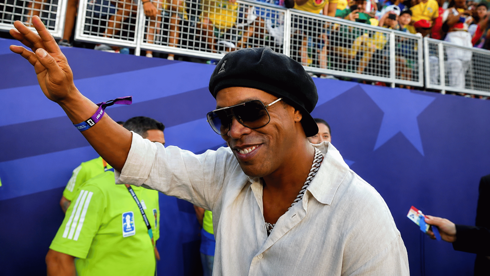 ronaldinho waving to fans during a public appearance at a football event with supporters in the background