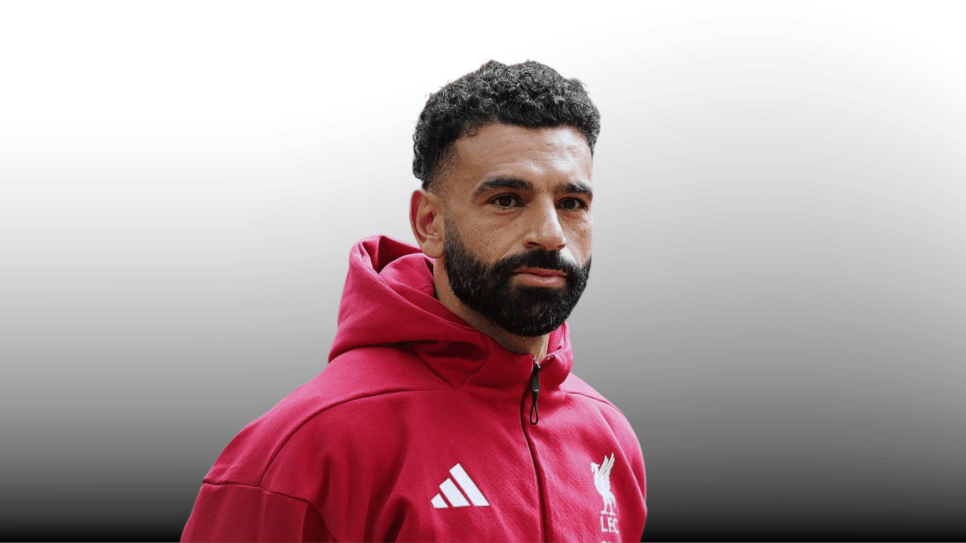 soccer player with short curly fade haircut full beard and red hoodie on gray gradient background