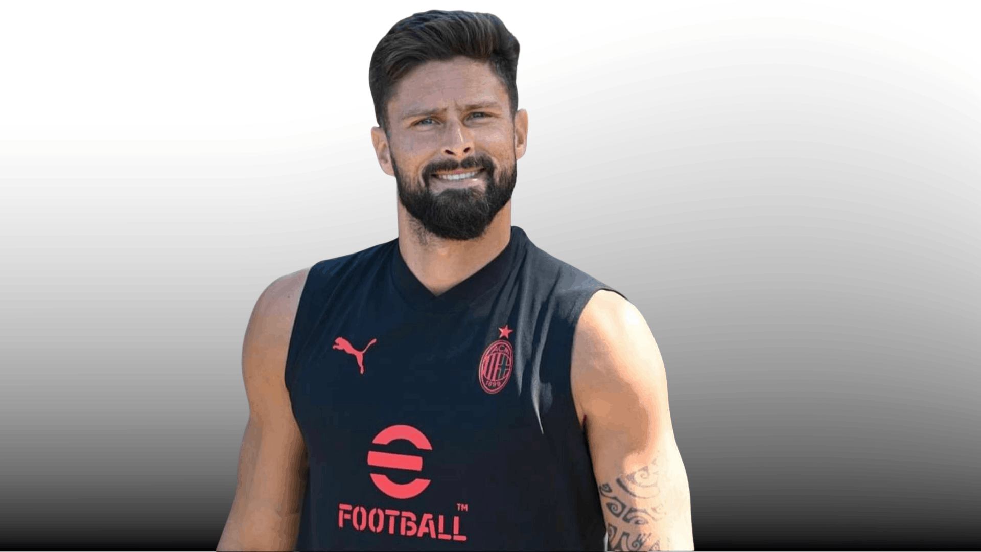 soccer player with voluminous quiff haircut full beard black sleeveless training top and arm tattoo