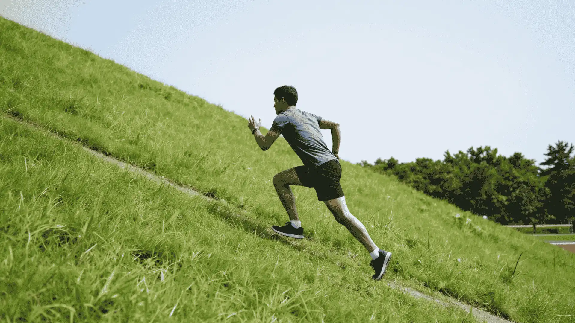 athlete sprinting up a grassy hill during incline speed training for football power and conditioning
