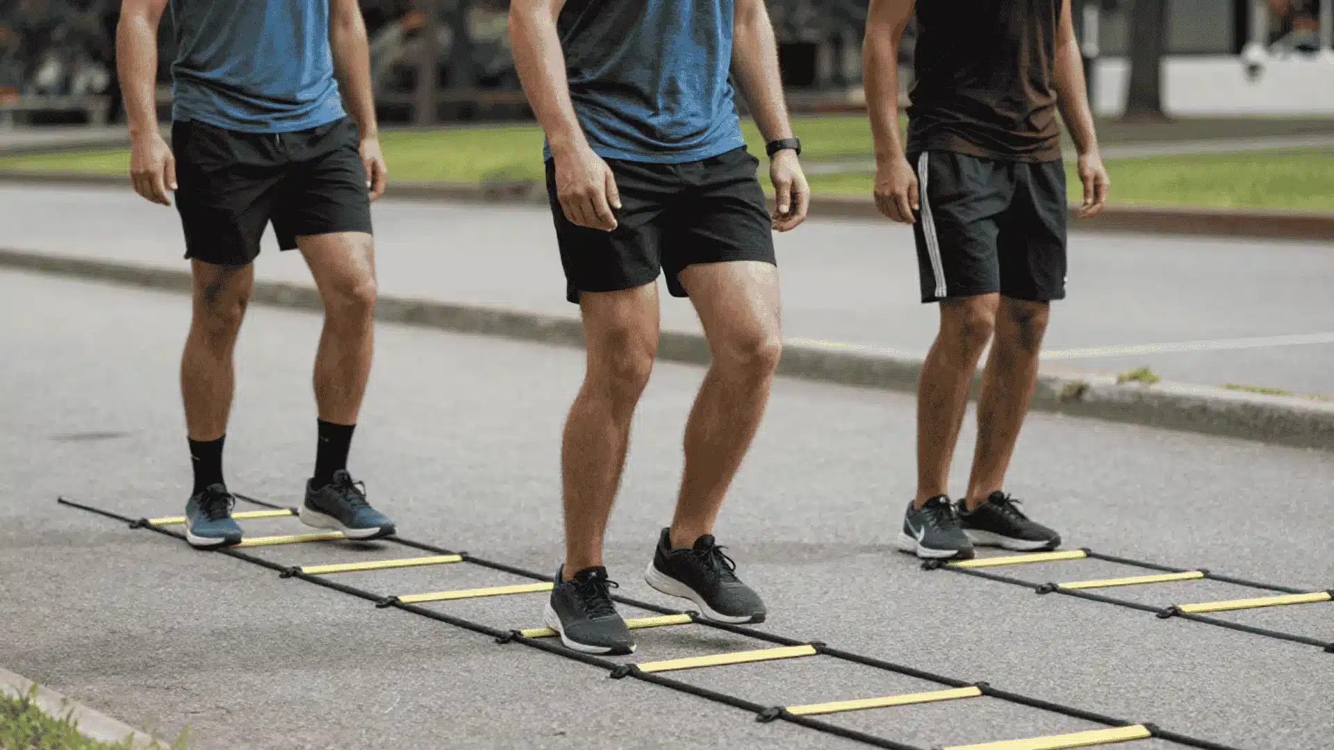 group of athletes moving through agility ladders on pavement during classic icky shuffle footwork drills