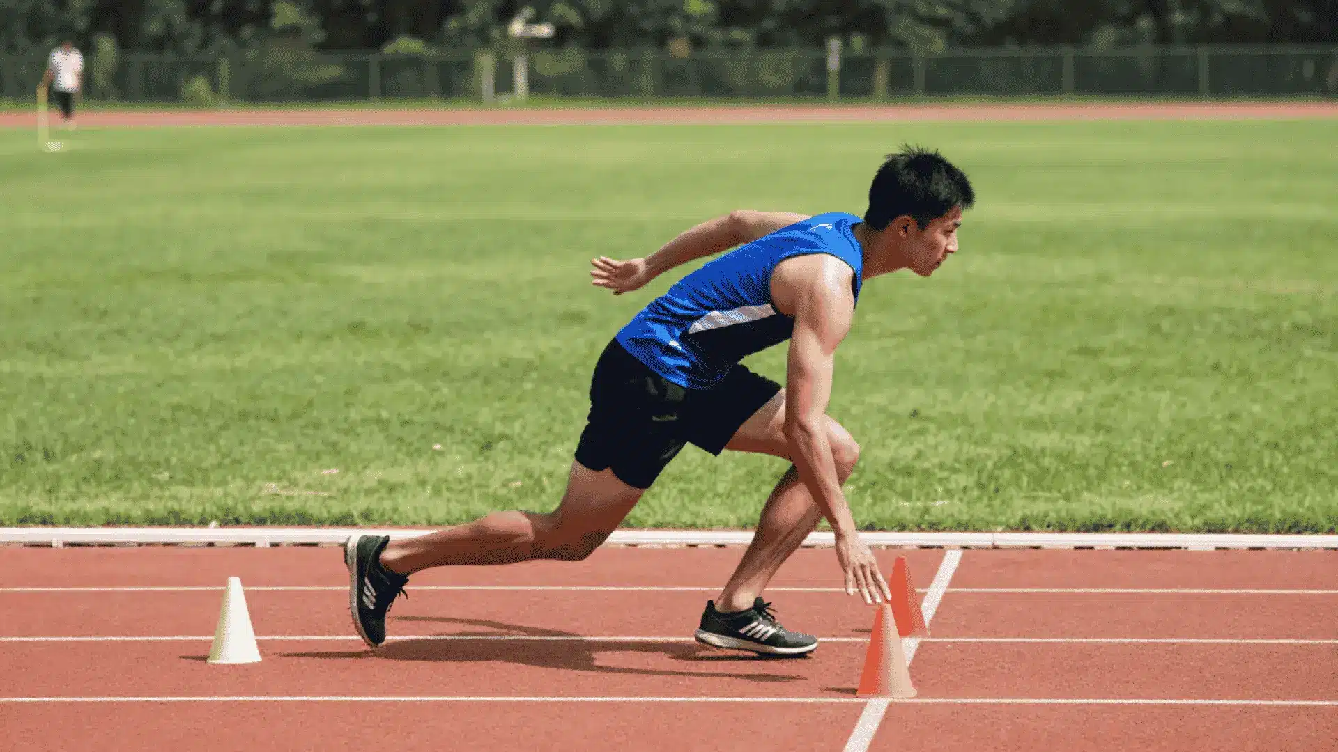 athlete cutting low between cones on an outdoor track during five ten five shuttle speed training