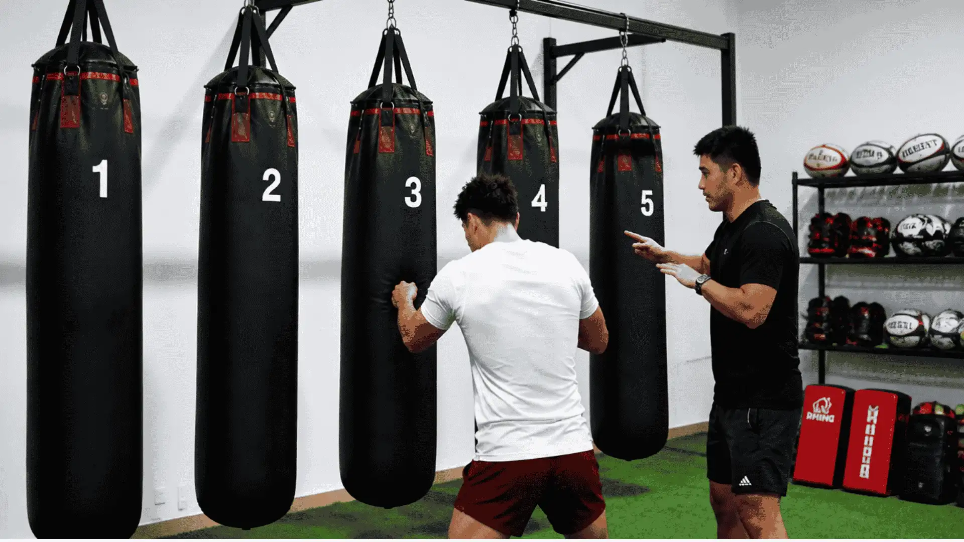 athlete practicing numbered gap reaction drills with a coach and hanging bags in an indoor training space