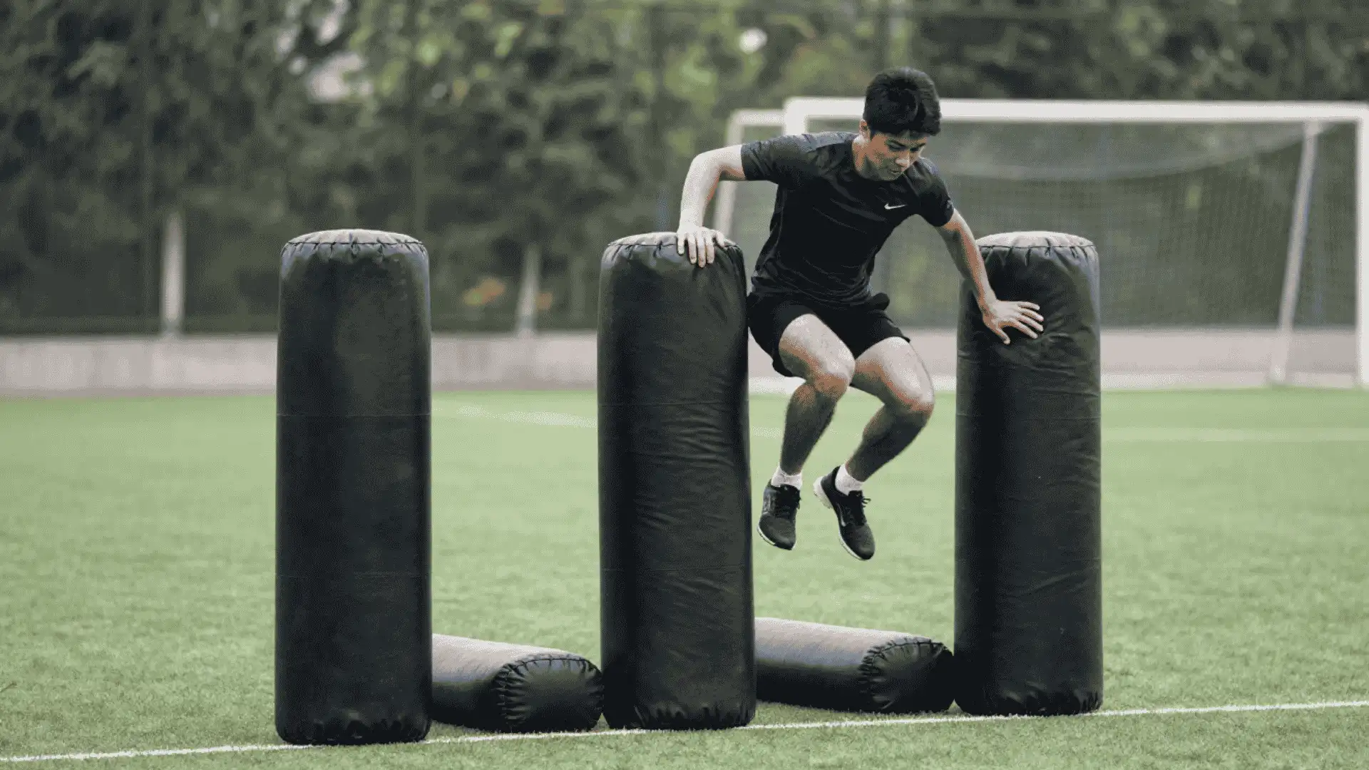 athlete jumping between padded bags on a football field during pop up bag collision training