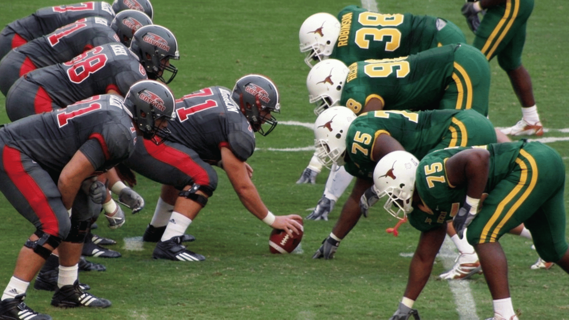 two football teams in uniform one in gray and the other in green crouch on the field in a ready position for a play