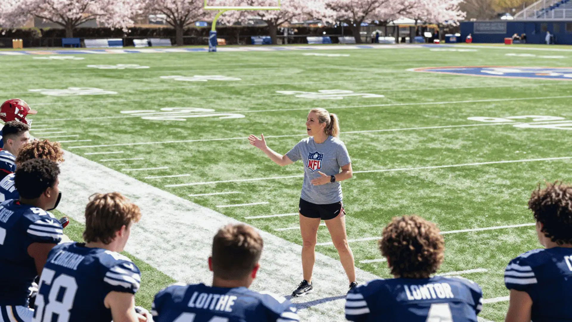 football coach explaining defensive strategy to players on field during practice session