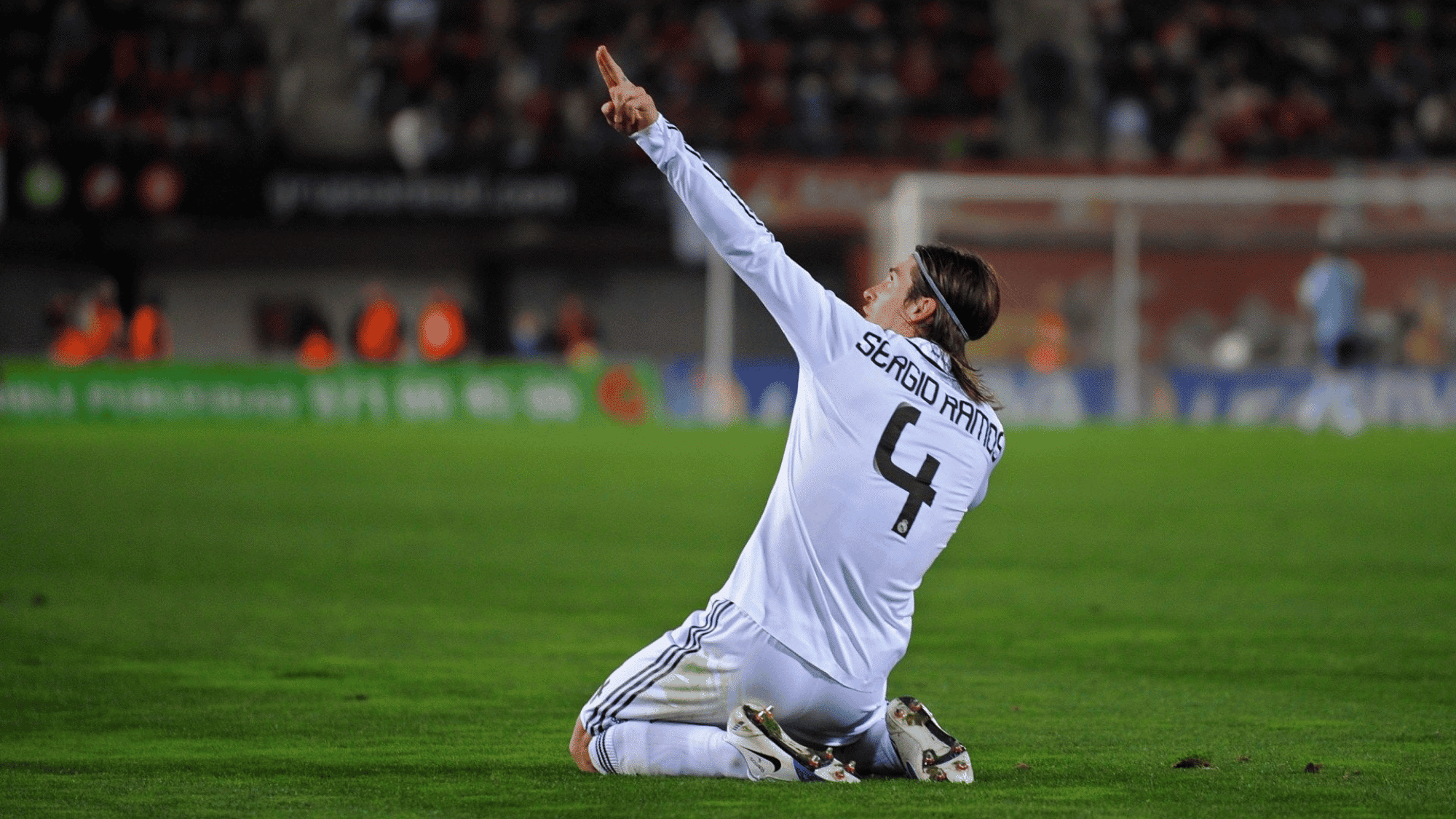 wide angle shot of sergio ramos celebrating with his hands in the air on the grass and blurry background