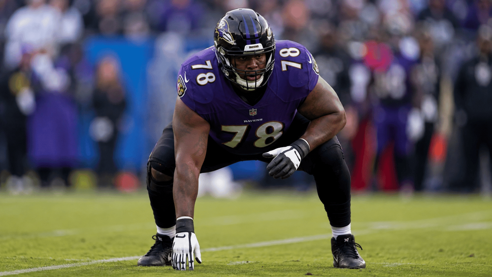 a baltimore ravens player number seventy eight crouches low showing his powerful build on the field