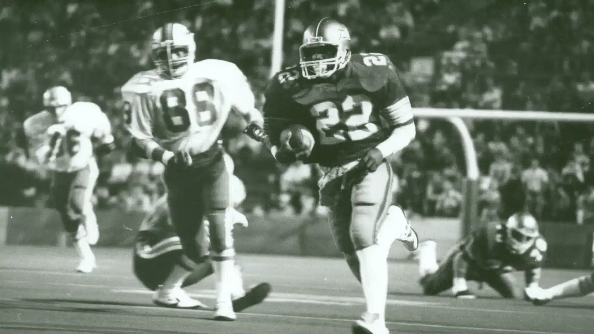 football player in dark uniform runs past defenders during a vintage action scene on the field