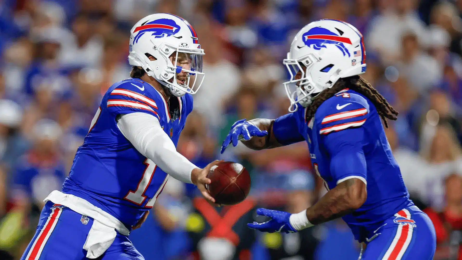 football quarterback handing ball to running back during offensive play in blue uniforms