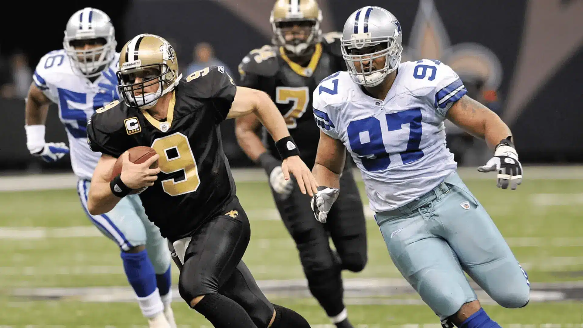football quarterback running with ball while defensive players chase him during a game