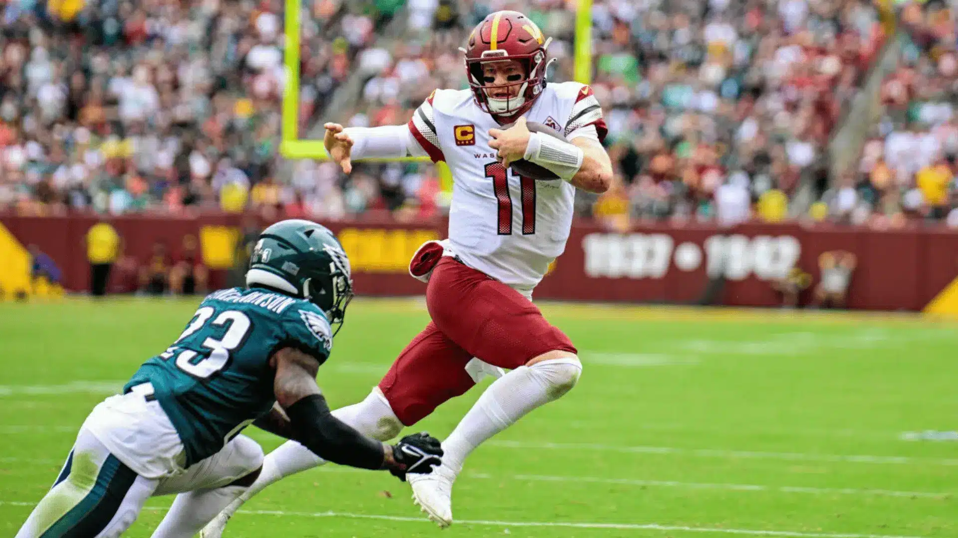 football quarterback scrambling away from defender during fast game action on the field