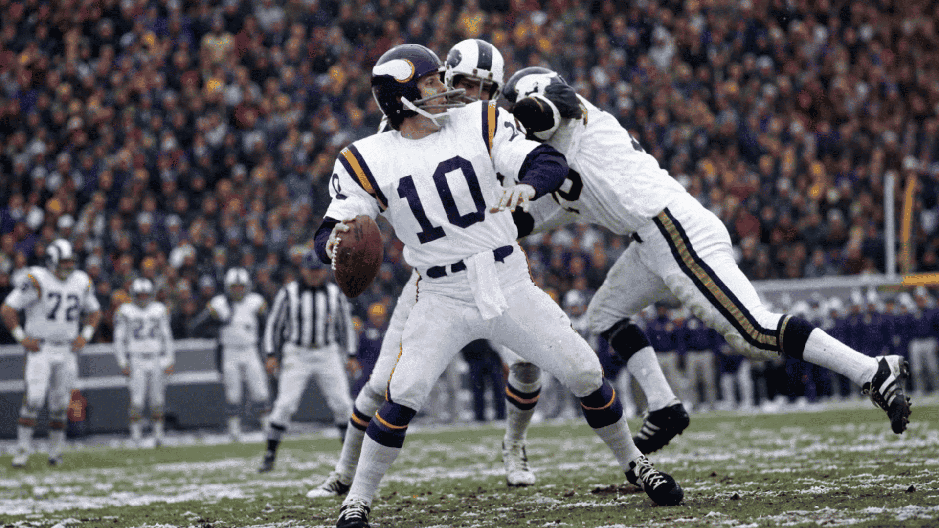quarterback in number ten jersey throws under pressure from defenders on a snowy football field