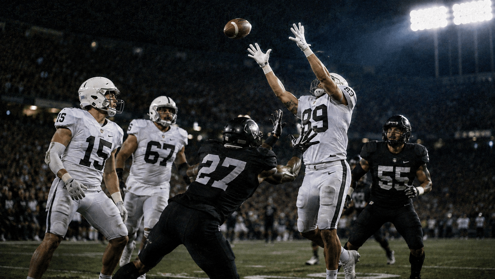 receiver leaps for the football as a defender challenges him under bright stadium lights