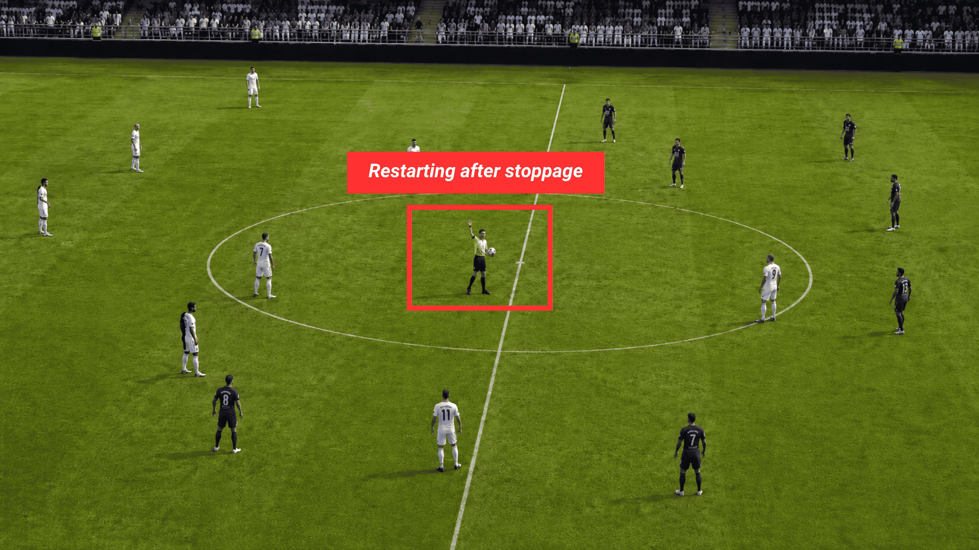 referee holding a soccer ball with one hand raised as players wait around the center circle for a restart