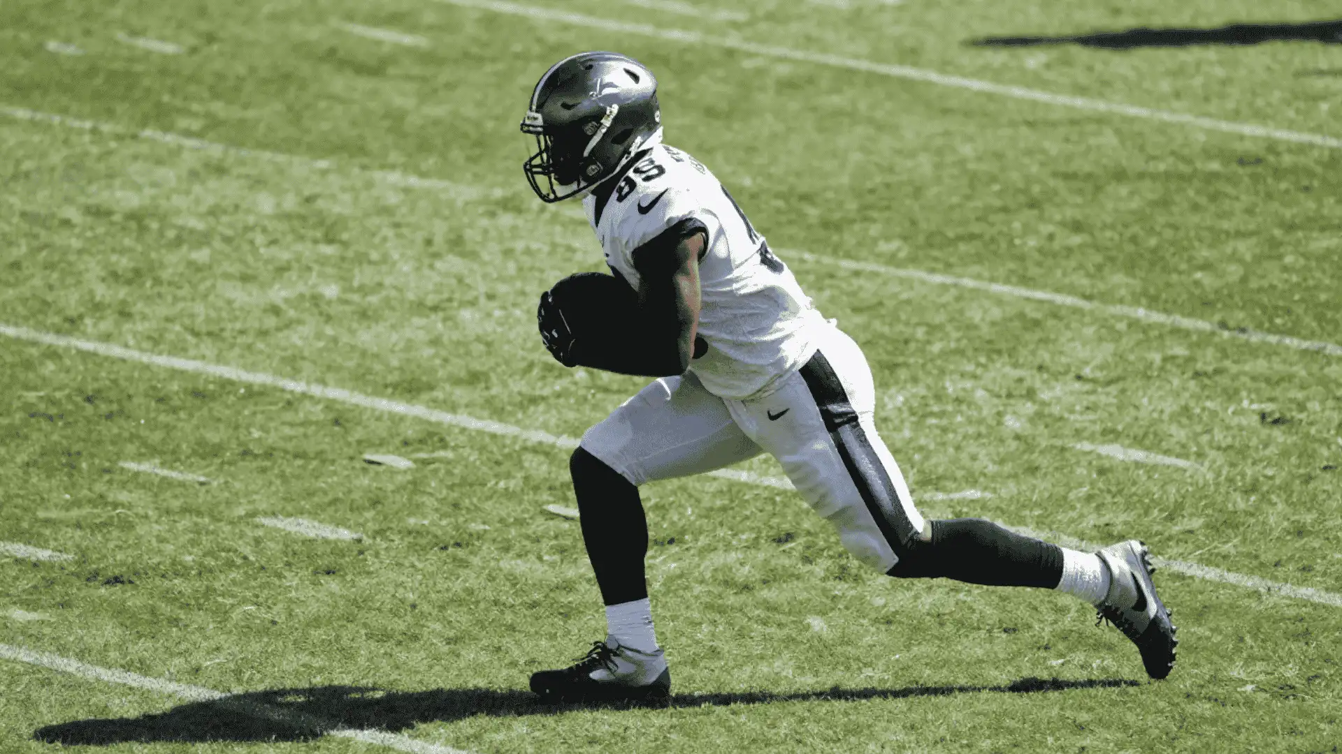 running back sprints with the football in open space during a bright daytime game on the field